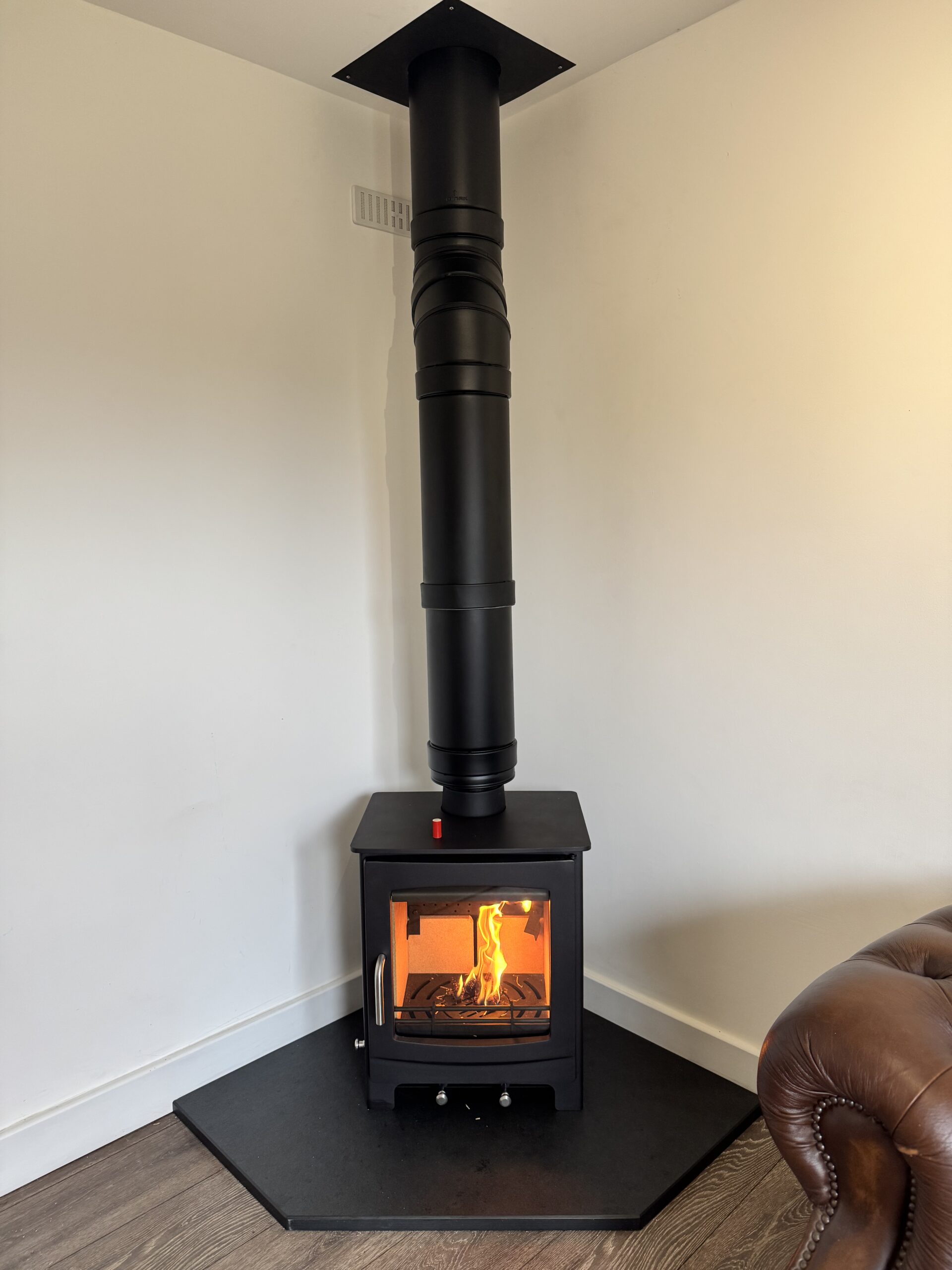 Log burner with a black flue installed inside a flat-roof extension